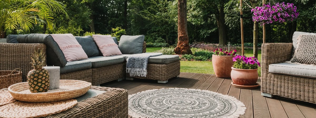 Stilvolle Möbel auf einer Holzterrasse in einem schönen grünen Garten