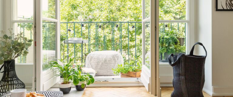 Offene Glastür von einem Wohnzimmer in einen Stadtgarten o