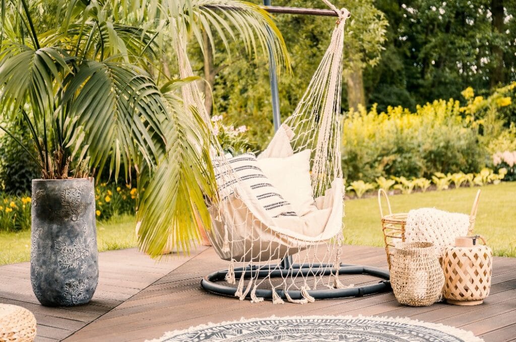 Sommer im grünen Garten mit einer Hängematte und einer Palme auf einer Terrasse.